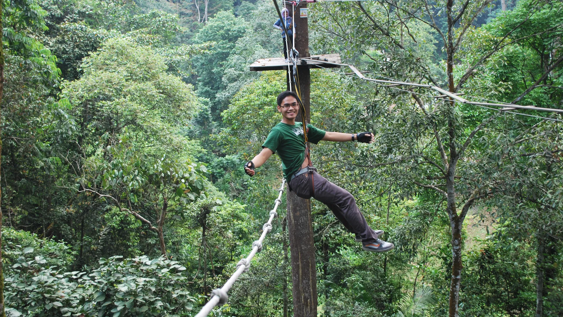Skytrex participant crossing a rope challenge above the forest in Melaka
